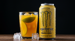 Can of Monster Juice with tropical fruit drink in a glass, side view
